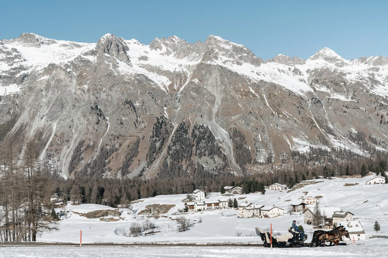 Pferdeschlitten vor einem Weiler im Val Fex