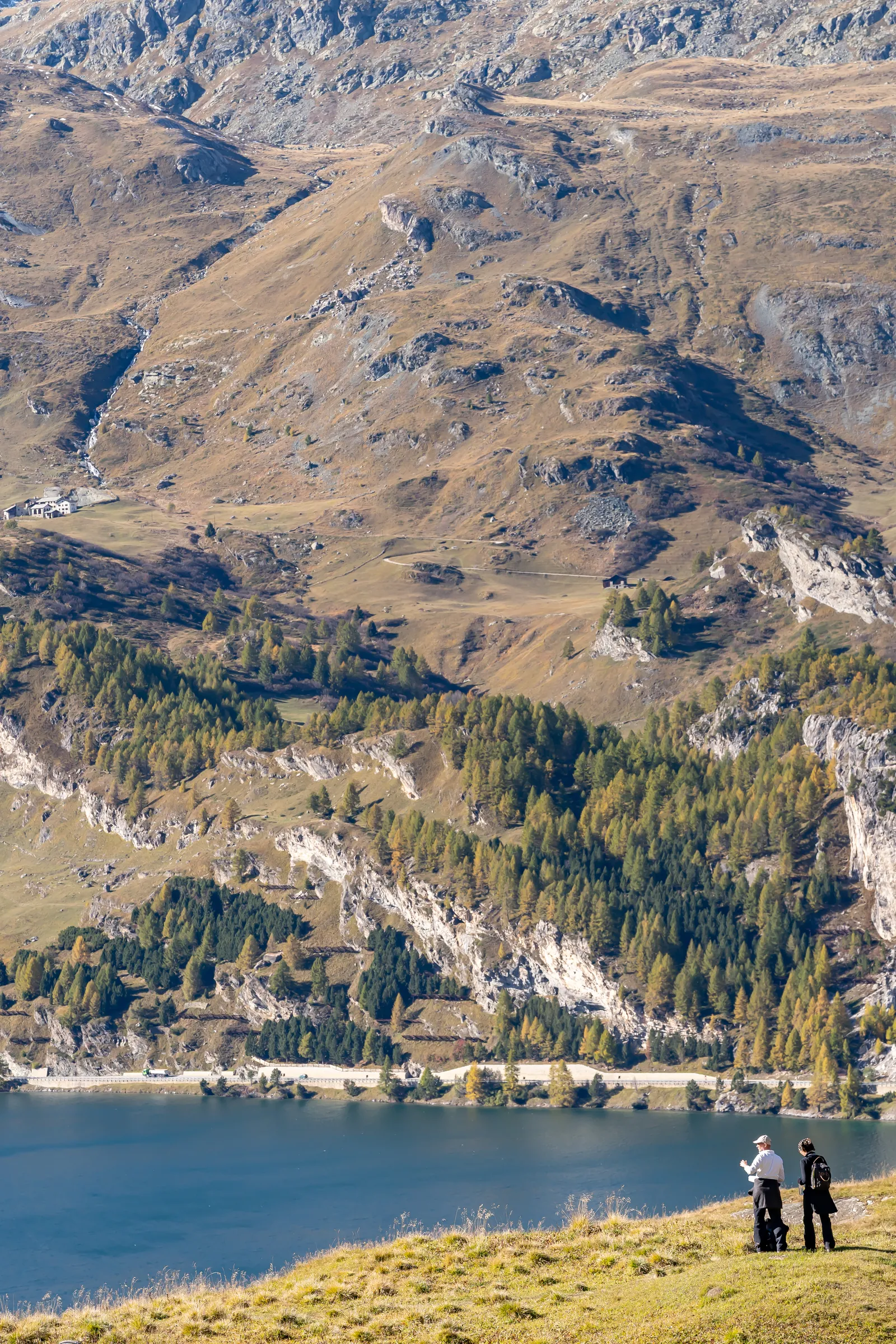 Due escursionisti su un pendio dorato alto sopra il lago di Sils