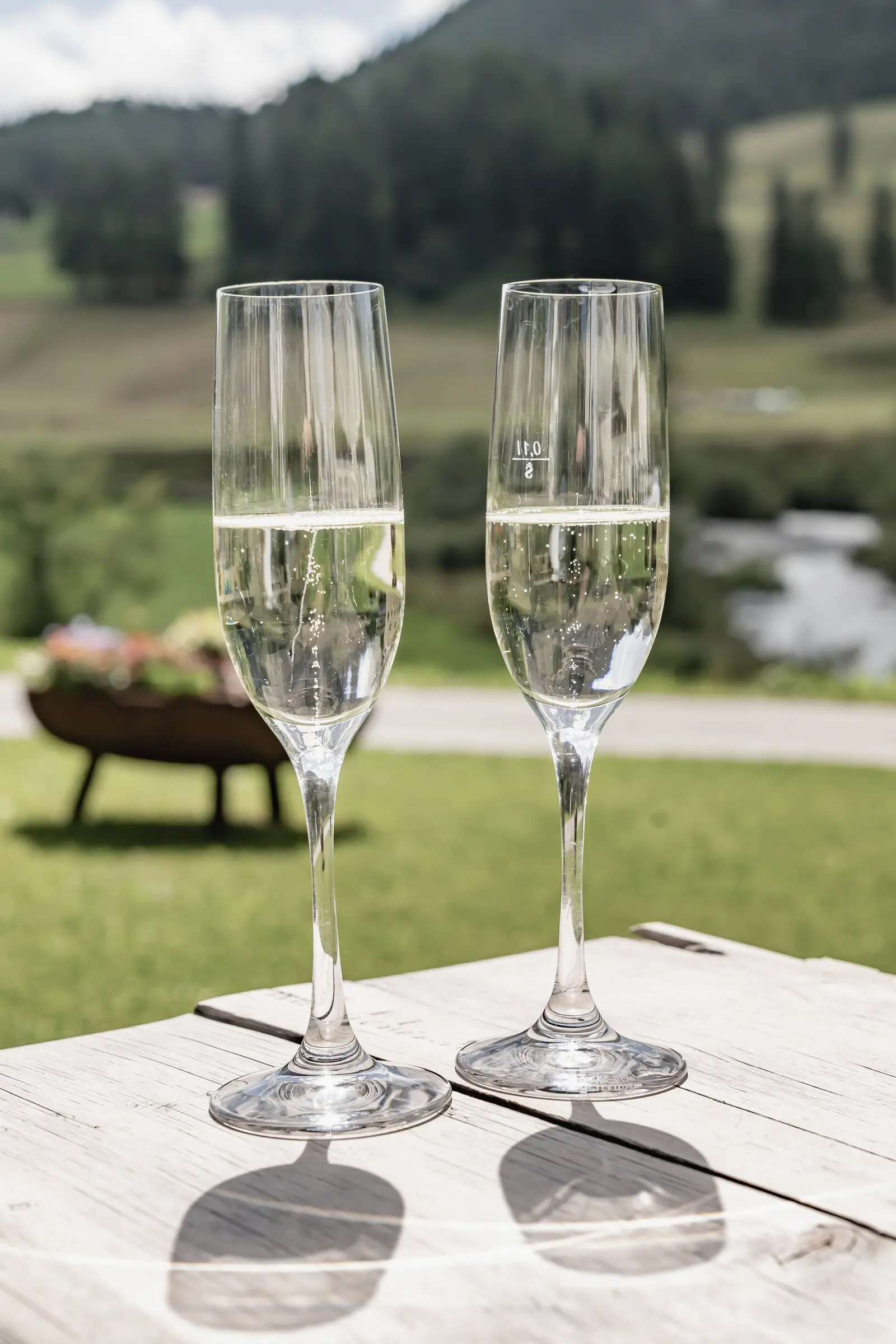 Prosecco on a wooden table by the meadow and stream