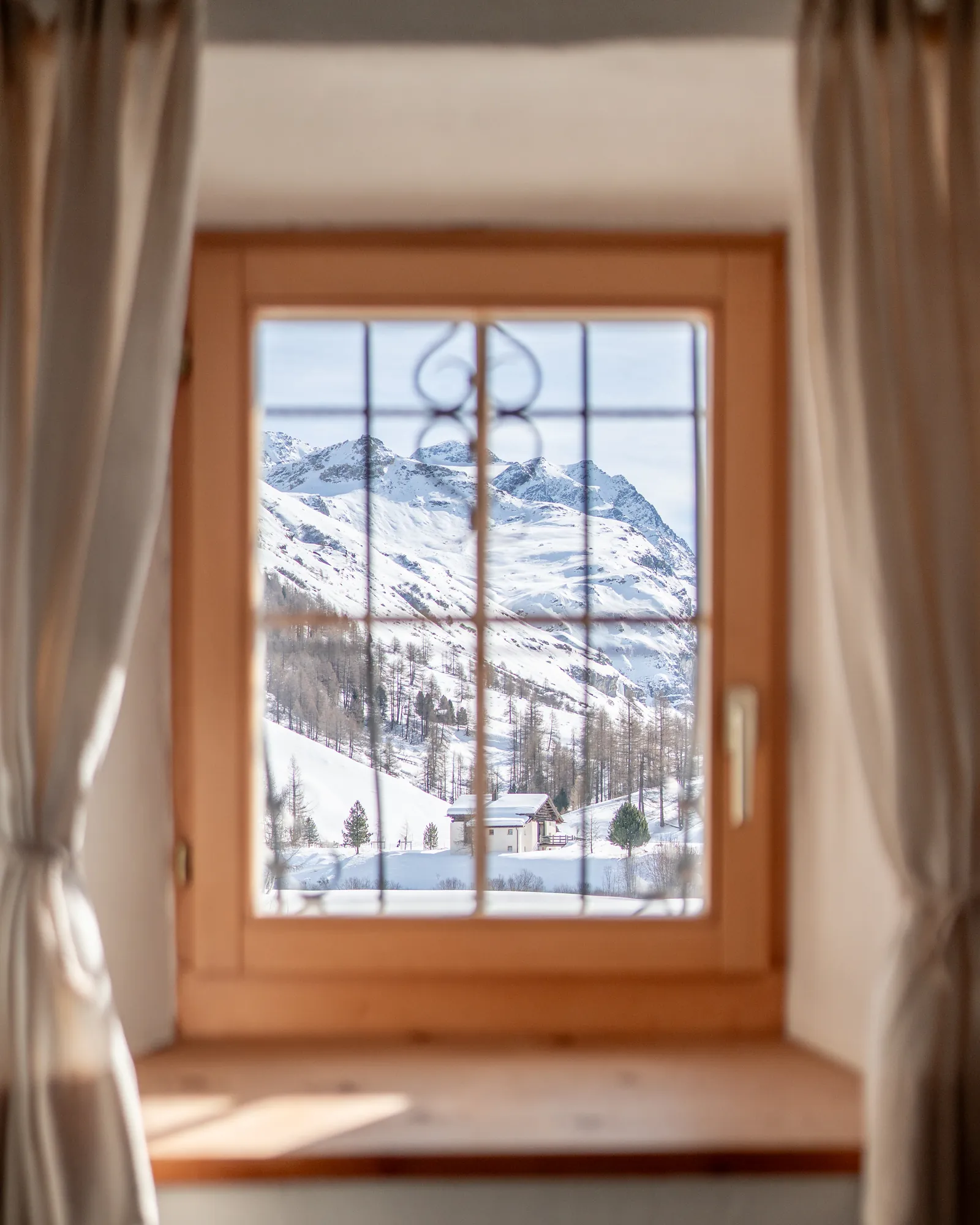 Zimmerfenster mit Blick auf verschneite Berge